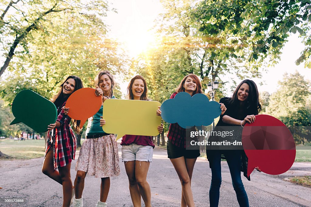 Happy friends with speech bubbles smiling to the camera