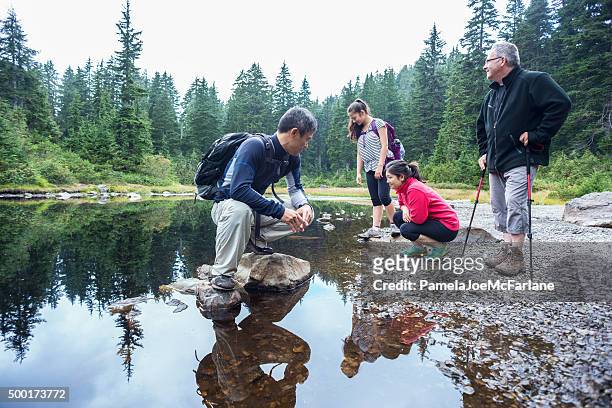 family of hikers resting at shoreline of alpine lake, canada - vancouver canada stock pictures, royalty-free photos & images