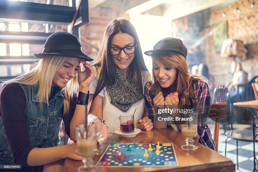 Glückliche Freunde spielen cross und Abschnitt Spiel in einem Café.