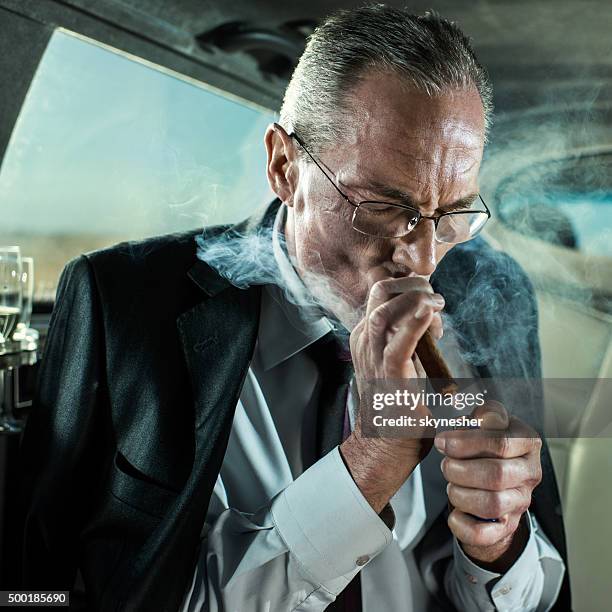 senior businessman in a limousine lighting up cuban cigar. - premium lighter stock pictures, royalty-free photos & images