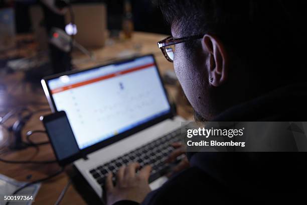 An attendee working on a Apple Inc. Laptop computer with a mobile device tethered to it participates in the TechCrunch Disrupt London 2015 Hackathon...