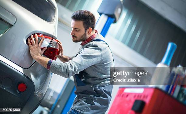 auto mechaniker ersetzt rücklicht auf ein fahrzeug. - rear light car stock-fotos und bilder