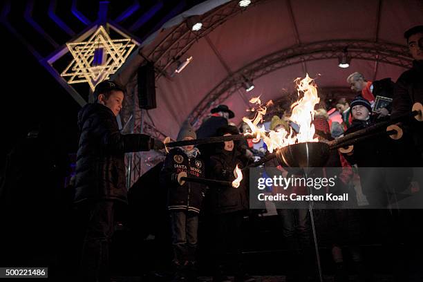 Children light torches at the ceremony of the Hanukkah menorah lighting at a public Menorah ceremony near the Brandenburg Gate on December 6, 2015 in...