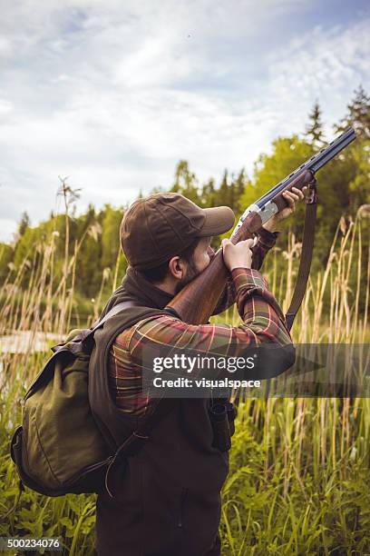 hunter pointing a gun to the sky in swamp - shotgun stockfoto's en -beelden