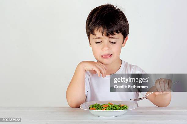 unhappy caucasian boy eating vegetables - picky eater stock pictures, royalty-free photos & images