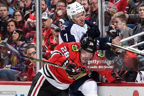 Ryan Garbutt of the Chicago Blackhawks checks Ben Chiarot of the Winnipeg Jets into the boards in the first period of the NHL game at the United...