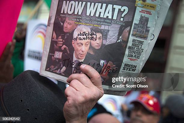 Demonstrator holds up a newspaper with a picture of Chicago Mayor Rahm Emanuel on the front during a march down State Street to protest the death of...