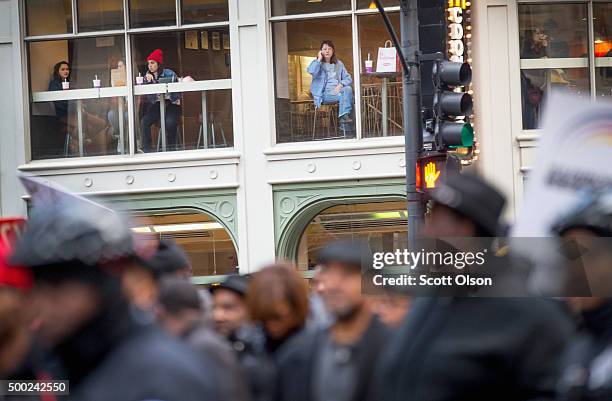 Diners watch from a restaurant window as demonstrators led by Rev. Jesse Jackson march through downtown to protest the death of Laquan McDonald and...
