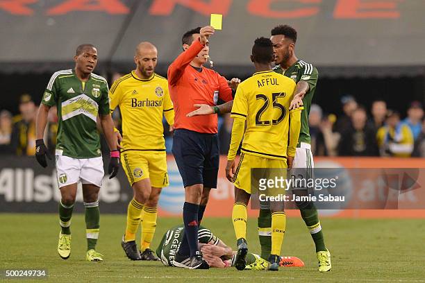 Referee Jair Marrufo issues a yellow card to Harrison Afful of the Columbus Crew SC after Afful took down Liam Ridgewell of the Portland Timbers in...