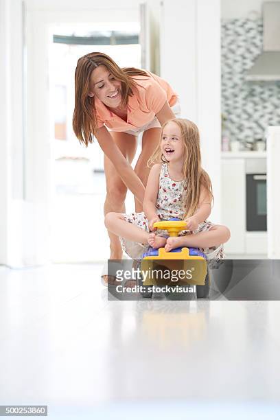 mother pushing daughter in toy car - skimpy girls stock pictures, royalty-free photos & images