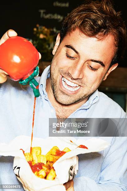 man pouring ketchup on to chips - tomato sauce stock pictures, royalty-free photos & images