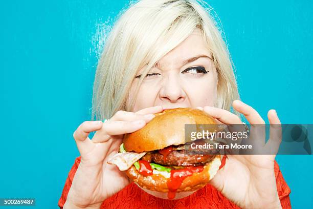 woman eating hamburger - ungesunde ernährung stock-fotos und bilder