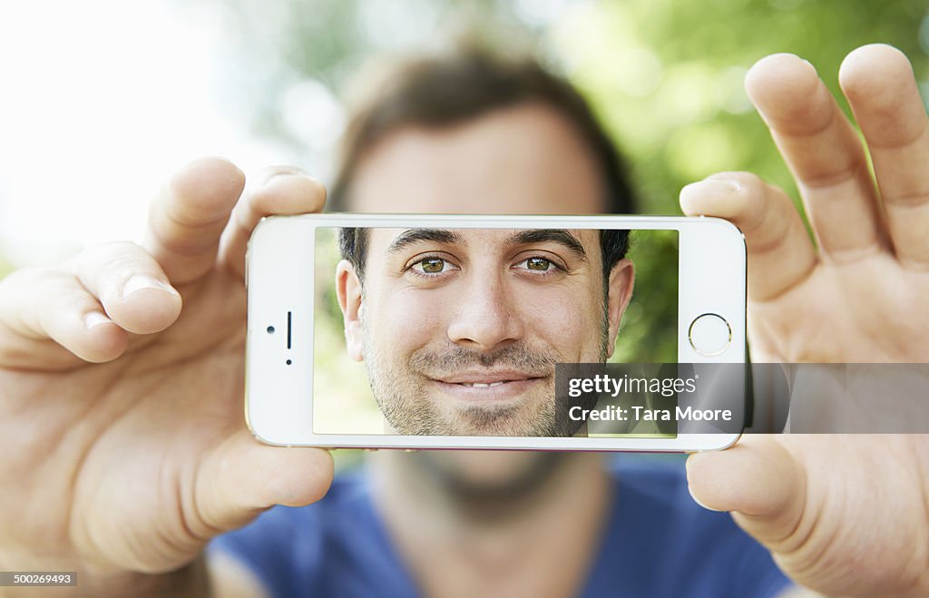 Man holding mobile with selfie on screen
