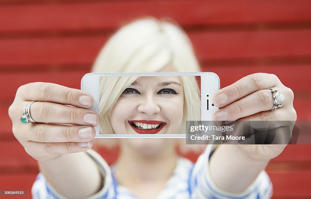 Woman holding up mobile with selfie on screen