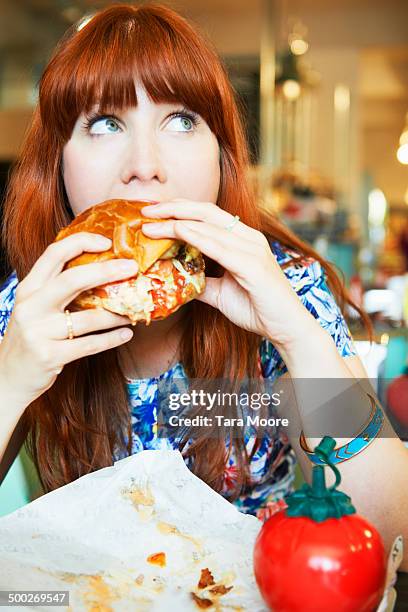 woman eating hamburger in cafe - seulement des adultes photos et images de collection