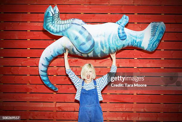 woman holding up toy dinosaur - strength stock-fotos und bilder