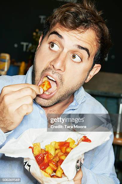 man eating bag of chips - chips bag stockfoto's en -beelden