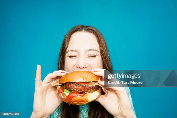 woman eating hamburger - woman junk food eating stockfoto's en -beelden