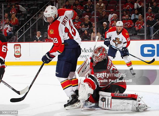 Goalie Cory Schneider of the New Jersey Devils stops a tipped shot by Reilly Smith of the Florida Panthers during the third period of an NHL hockey...