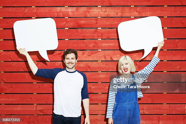man and woman holding up speech bubbles - speech bubble stock pictures, royalty-free photos & images