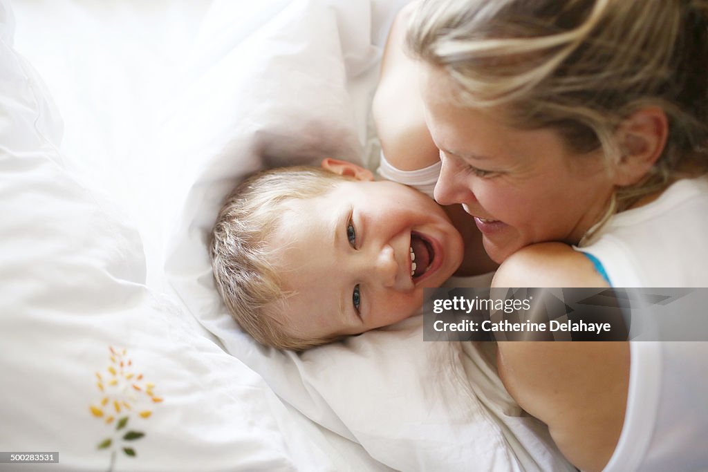 A 3 years old boy in his bed with his mom