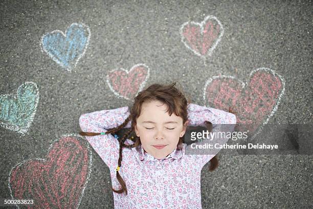 a girl closes her eyes, laying on a decorated road - gebloemd shirt stockfoto's en -beelden