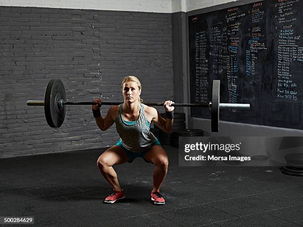 female gym performing back squat - crouching stock pictures, royalty-free photos & images