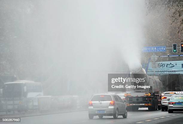 Vehicle is driven along a road and squirts water into the air to dispel smog on December 7, 2015 in Jinan, China. China's National Meteorological...