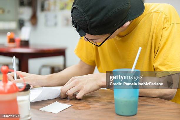 young man completing paperwork in a cafe - tribal head gear in china stock pictures, royalty-free photos & images