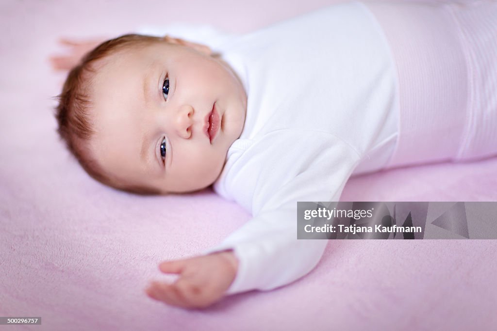 Cute five week old Baby Girl lying on pink blanket