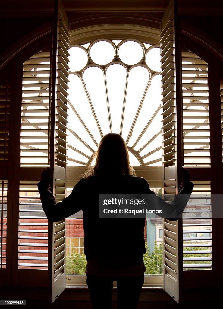 Silhouette of girl looking out window