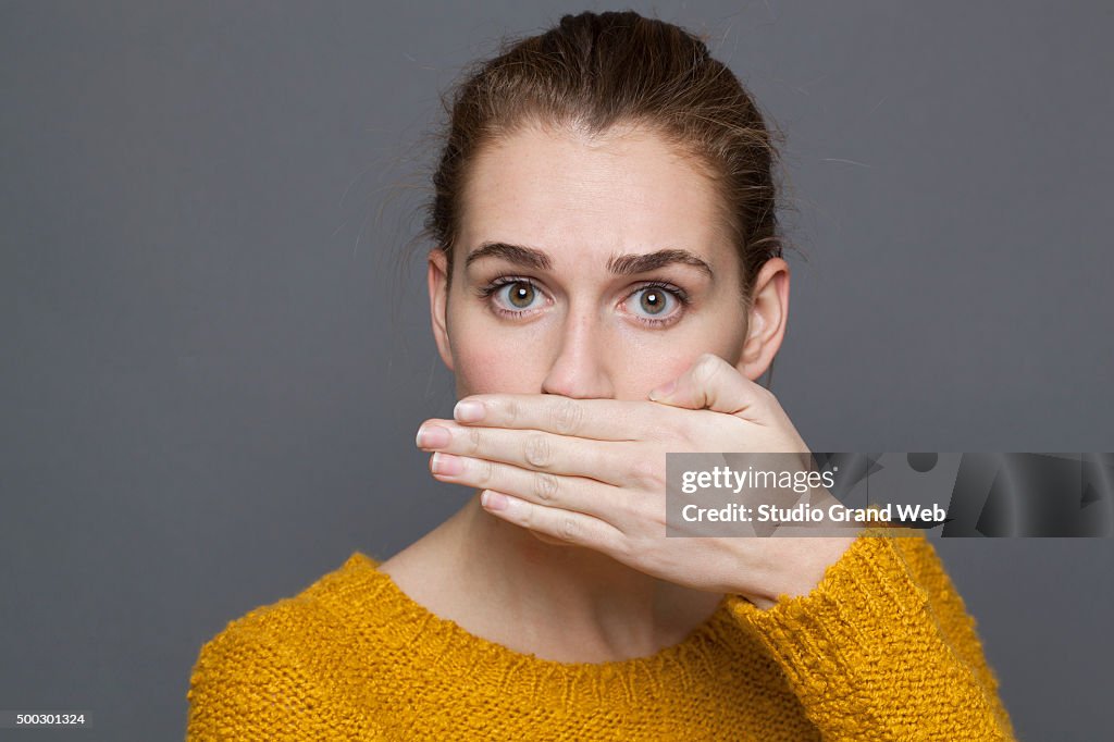 Retrato de mulher jovem surpreendida, cobrindo a sua boca de silêncio
