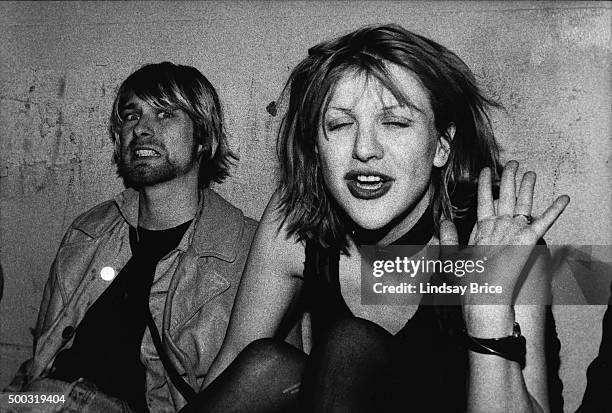 Kurt Cobain and Courtney Love pose for photograph, Kurt grimacing for the camera and Courtney waving, on VIP balcony during Mudhoney concert at the...