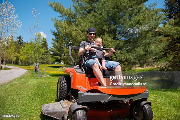 involved dad mowing law with his baby boy - lawn tractor stock pictures, royalty-free photos & images