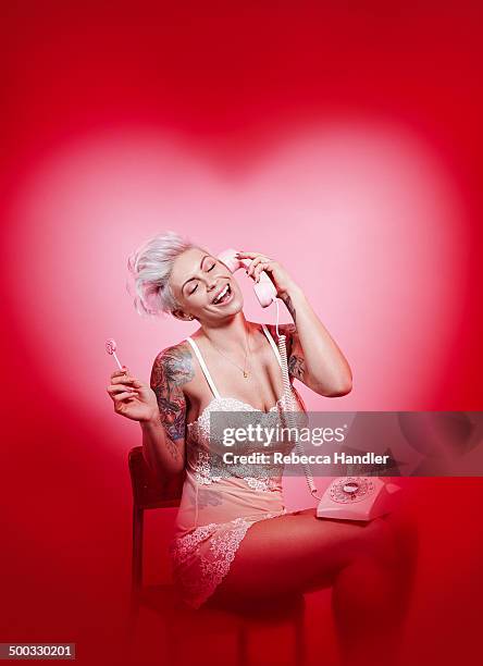 adult female talking on phone with pink backdrop - heart chair design stock pictures, royalty-free photos & images