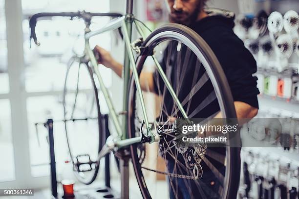 mechanic repairing a bike - reparatiewerkplaats stockfoto's en -beelden