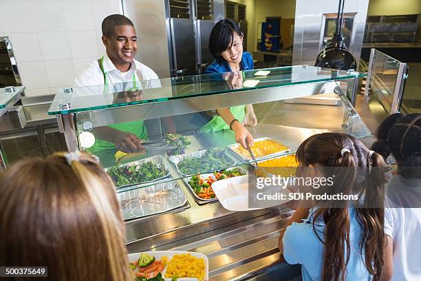 school cafeteria worker mit gesunden lebensmitteln für studenten - schulessen stock-fotos und bilder