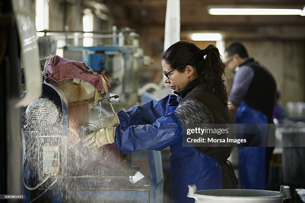 Female worker trimming glass vase