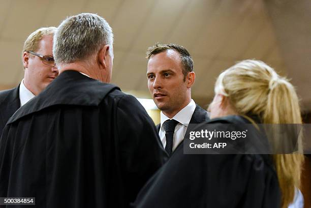 South African paralympian Oscar Pistorius speaks with lawyer Barry Roux and his legal team during a break in a bail hearing at the Pretoria High...