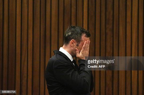 Former Paralympic champion Oscar Pistorius places his hands on his face as he stands in the dock at the North Gauteng High Court in Pretoria, South...