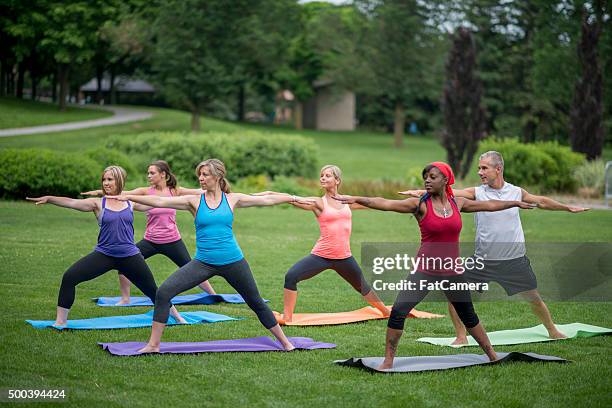 reaching forward in warrior ii pose - yoga outdoors stock pictures, royalty-free photos & images