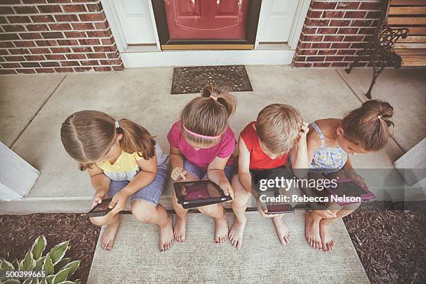 Children on front stoop using electronic devices