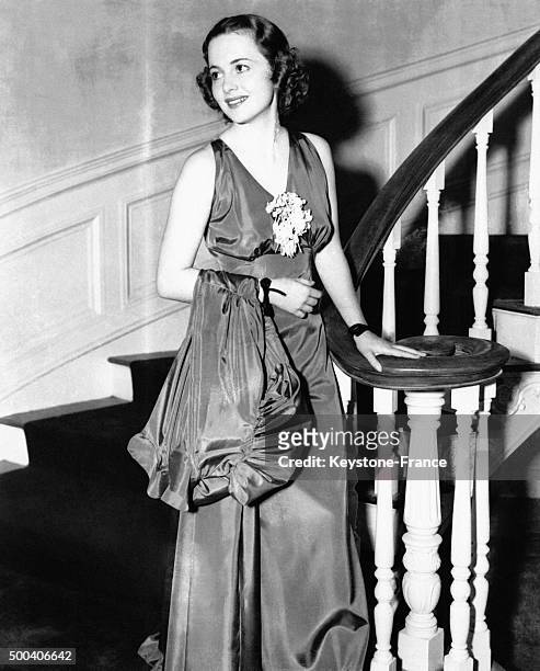 Olivia de Havilland portant un elegant ensemble du soir en taffetas compose d'une robe longue et d'un manteau, en 1936 a Hollywood, Californie.