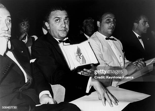 During Cannes Film Festival, Federico Fellini prestigiously holds up the Golden Palm he received for his film 'La Dolce Vita' on May 21, 1960 in...