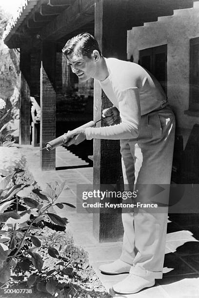 Acteur americain Clark Gable, passionne de jardinage, arrose ses fleurs dans sa villa de Beverly Hills le 1er decembre, 1932 a Berverly Hills,...