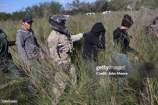 Border Patrol agent leads undocumented immigrants after capturing them near the U.S.-Mexico border on December 7, 2015 near Rio Grande City, Texas....