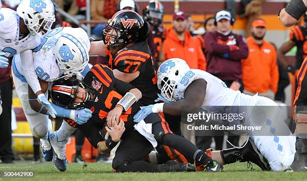 Quarterback Michael Brewer of the Virginia Tech Hokies is hit by defensive tackle Nazair Jones and defensive tackle Justin Thomason of the North...