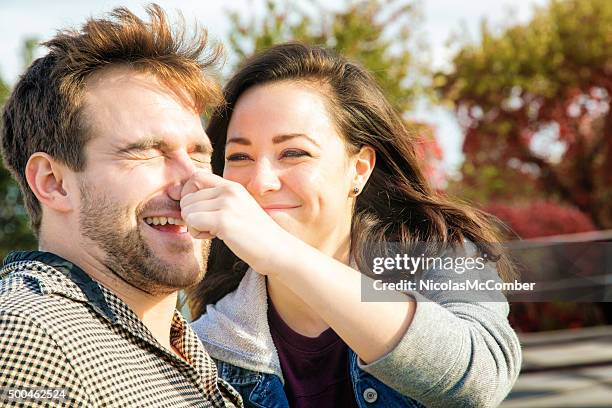 young american woman teasing her boyfriend by pincing his nose - pinching nose stockfoto's en -beelden