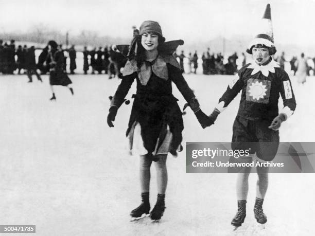 Two modern Chinese girls in flapper carnival dress and unusual makeup enjoy ice skating on the lake near the Winter Palace, Beijing, China, 1927.