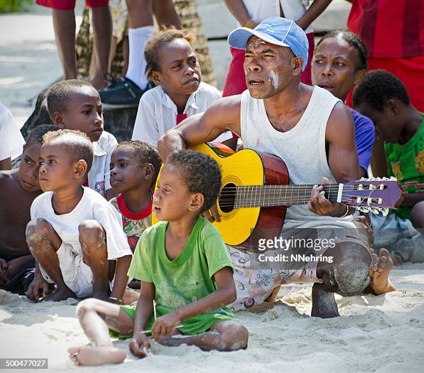 musician on beach in indonesian village - west papua stock pictures, royalty-free photos & images